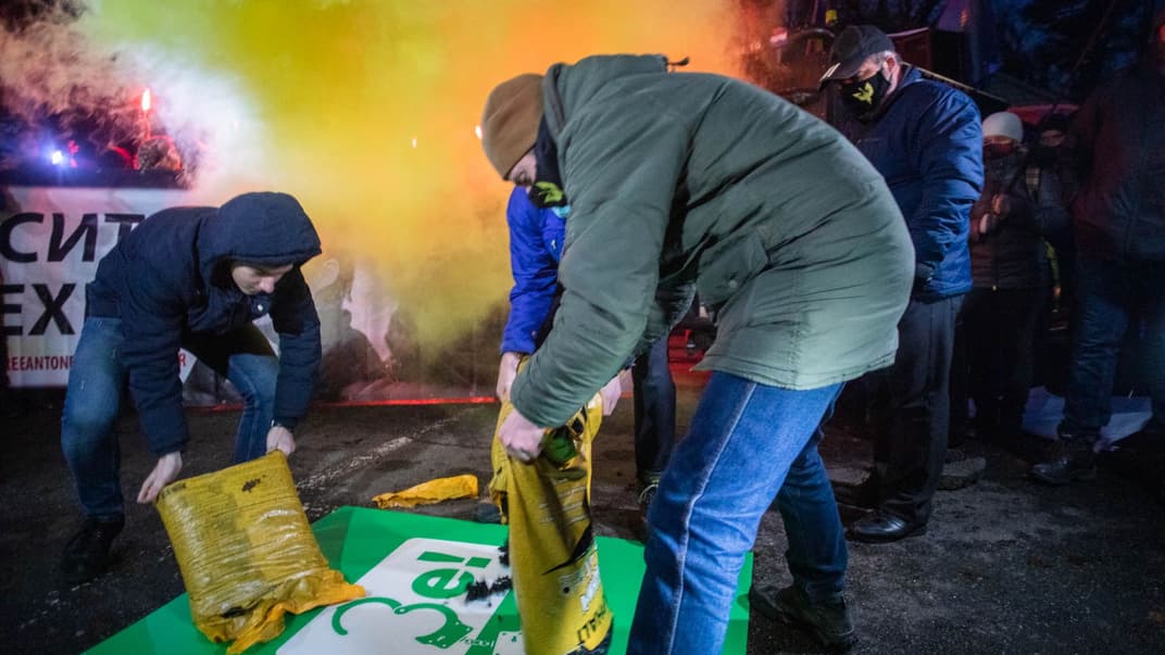 Активісти засипають асфальтом плакат із виборчою символікою президента України Володимира Зеленського