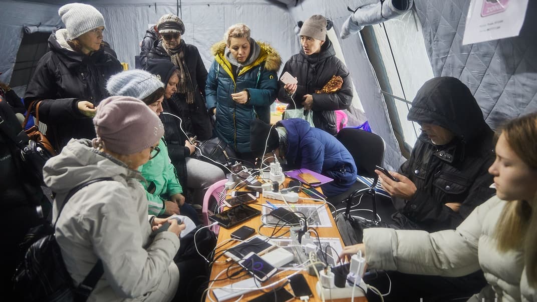 Люди заряджають телефони в «Пункті незламності» в Соломʼянському районі Києва, 24 листопада 2022 року