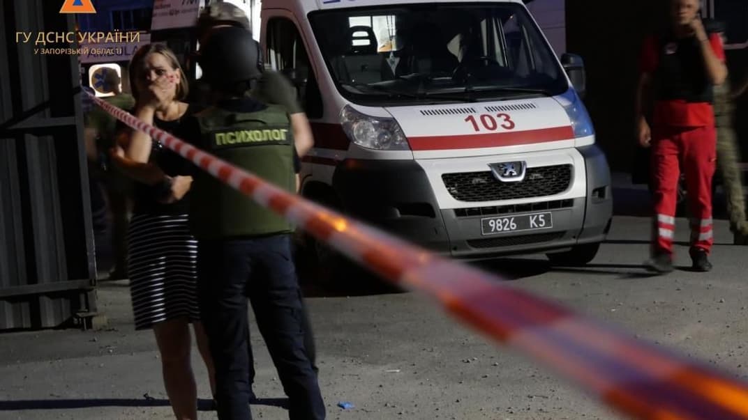 Психолог успокаивает женщину на месте российского удара по Запорожью, 9 августа 2023 года