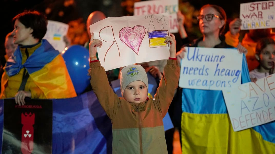 Мальчик держит баннер во время протеста украинцев против российских ударов по украинским городам в Бухаресте, 10 октября 2022 года