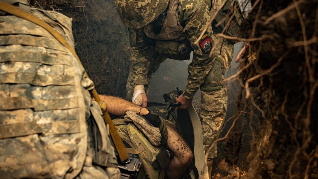 Бойові медики витягують пораненого бійця з поля бою