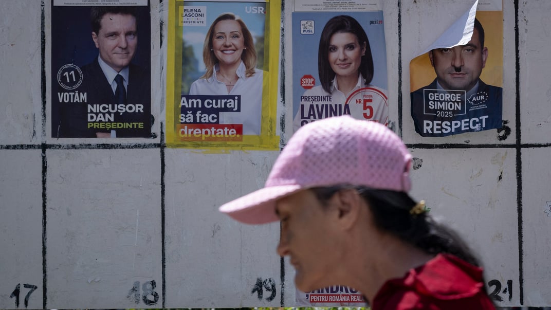 Жінка проходить повз передвиборчі плакати напередодні першого туру повторних президентських виборів у Румунії, Джурджу, 3 травня 2025 року