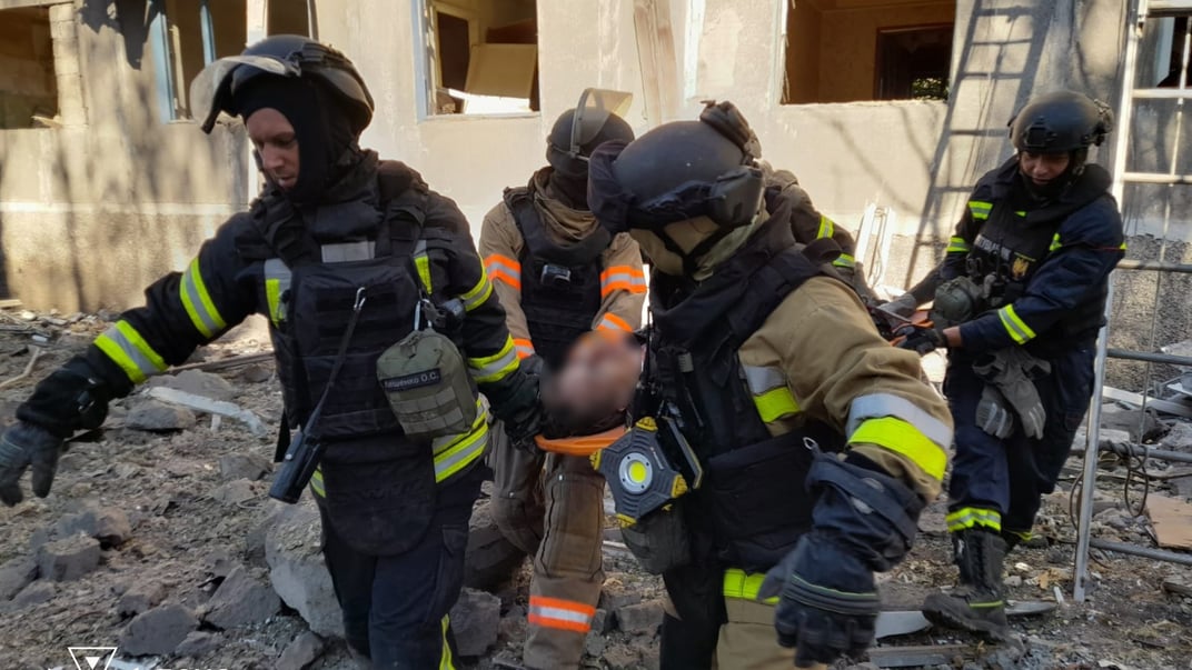 Спасатели выносят человека после российского авиаудара по жилой застройке Доброполья, 18 августа 2025 года