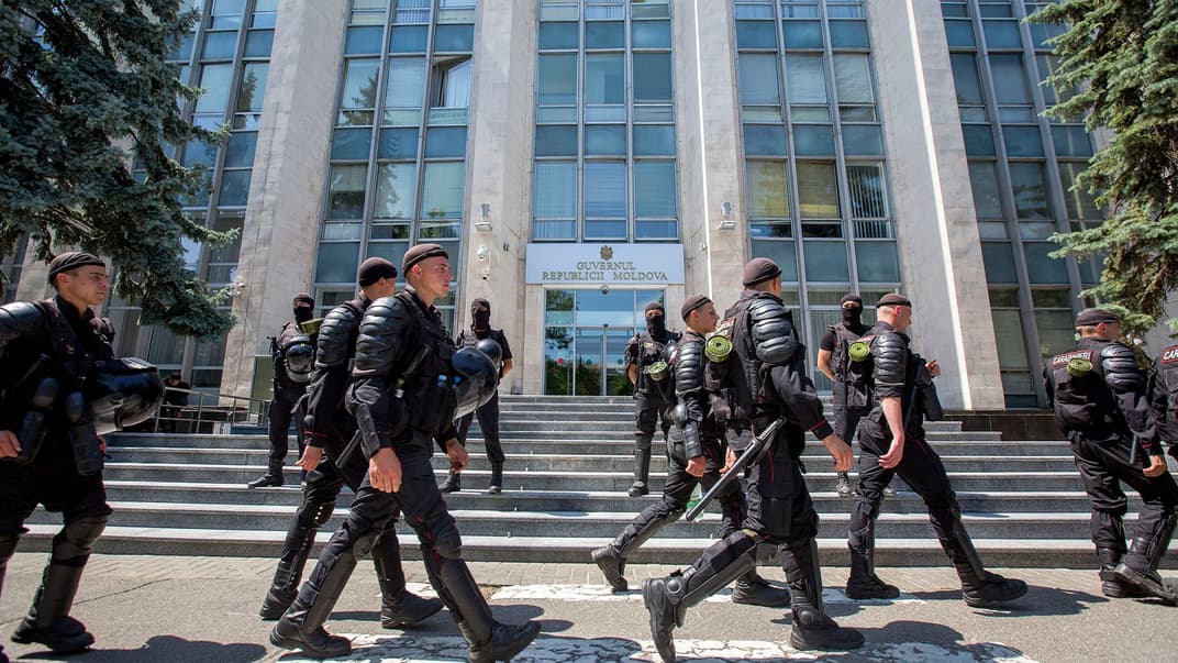 Поліцейські крокують повз будівлю Уряду, вхід до якої намагаються блокувати прихильники Демократичної партії Молдови. Кишинів, Молдова, 13 червня 2019 року