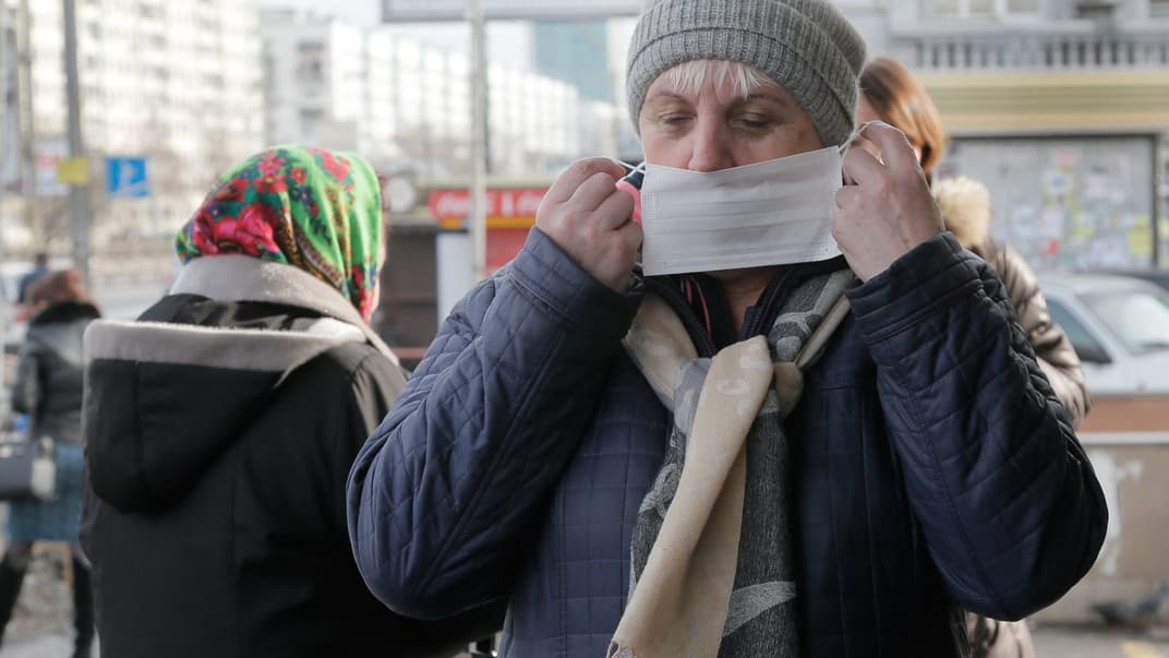 Женщина надевает маску на улице Киева, Украина, 3 февраля 2016 года