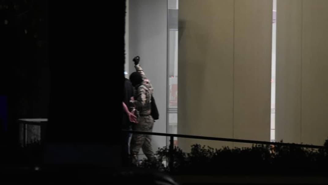 Мужчина, захвативший заложников в отделении банка, выходит с тремя людьми. В вытянутой руке он держит предмет, похожий на гранату. Зугдиди, Грузия, 21 октября 2020 года