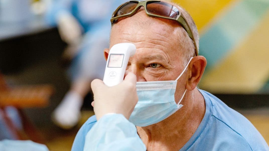 Врач проводит температурный скрининг перед прививкой вакциной от COVID-19, Ужгород, 19 июня 2021 года