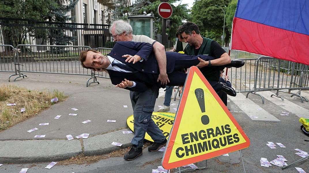 Активісти несуть воскову фігуру Емманюеля Макрона до російського посольства в Парижі