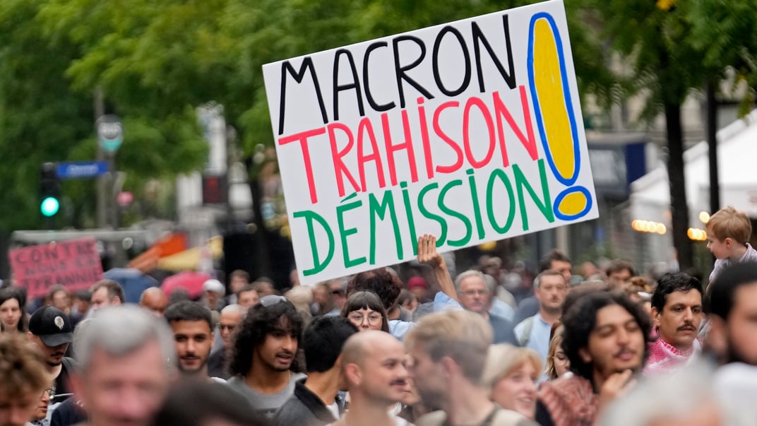 Демонстрант держит плакат с надписью «Макрон — измена, отставка!» во время антиправительственных протестов в Париже, 7 сентября 2024 года