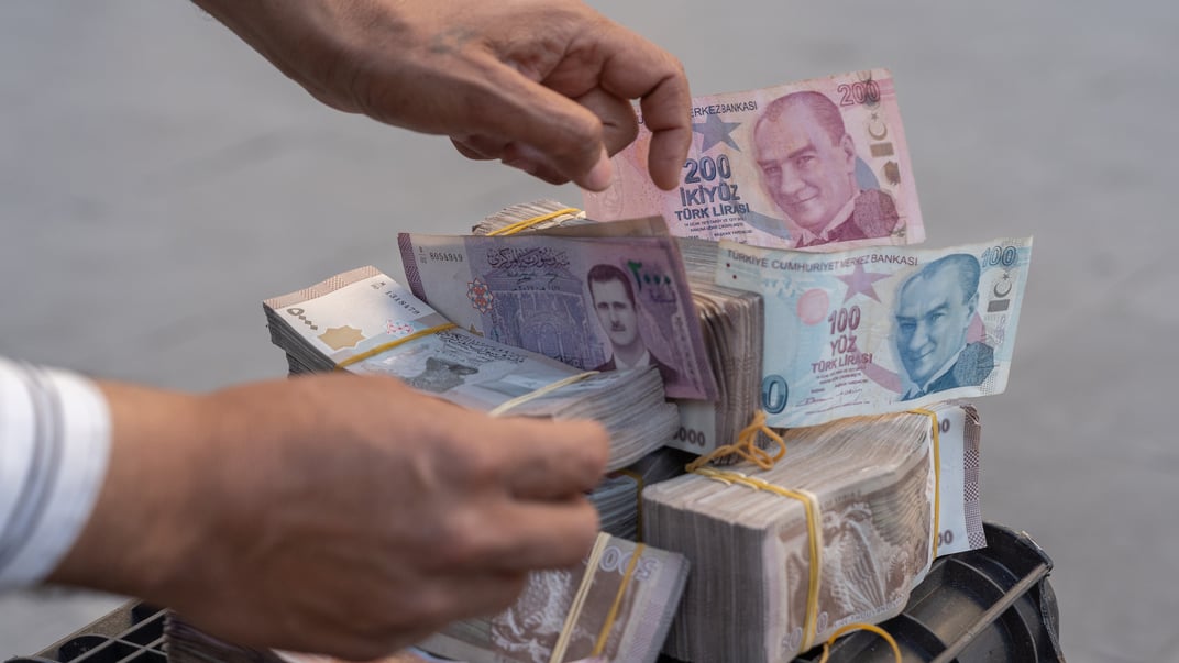 Чоловік розкладає пачки банкнот сирійських фунтів біля придорожнього «обмінника валют», Дамаск, Сирія, 19 січня 2025 року