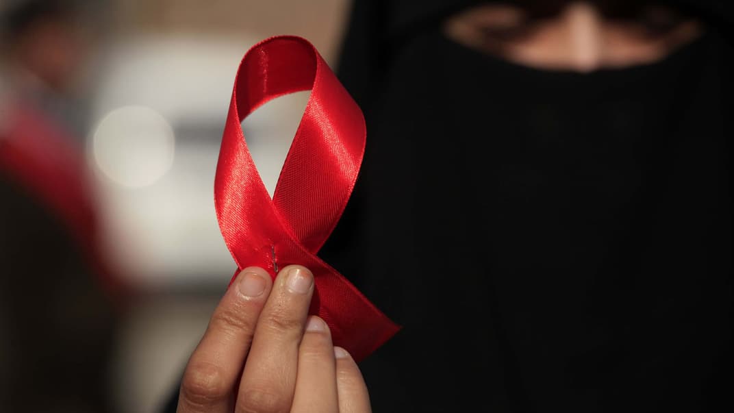 Женщина держит Красную ленточку во время акции с целью повышения осведомленности о ВИЧ и СПИД во Всемирный день борьбы со СПИДом в Пешаваре, Пакистан, 01 декабря 2016 года.