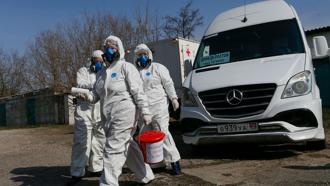 Работники в защитных костюмах дезинфицируют микроавтобус, который перевозит пассажиров из оккупированного Донецка в российский город Ростов, Донецк, Украина, 25 марта 2020