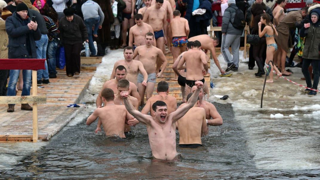 Люди пірнають у крижану воду річки Дніпро в Києві під час традиційних купань на Водохреще, 19 січня 2016 року
