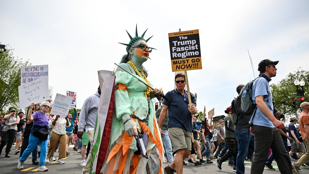 Протестувальники тримають плакати під час маршу до Білого дому у Вашингтоні, 19 квітня 2025 року
