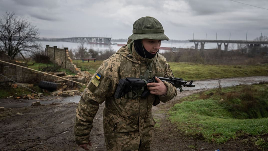 Украинский военный патрулирует территорию возле Антоновского моста, разрушенного российскими войсками после ухода из Херсона, Украина, 8 декабря 2022 года