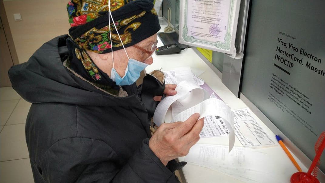 Женщина в медицинской маске платит за жилищно-коммунальные услуги в банке во время карантина, Киев, 15 мая 2020 года