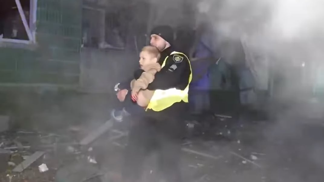 Поліціянт виносить на руках дитину з місця російського обстрілу у Сумах, 17 листопада 2024 року