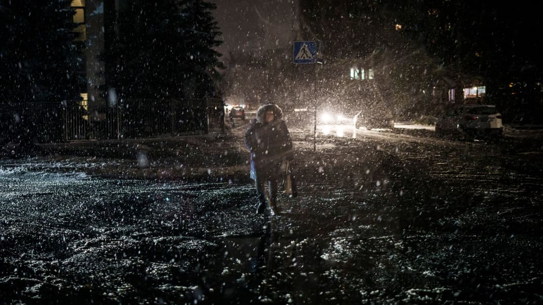 Жінка переходить вулицю під час снігопаду, коли тривають відключення електроенергії в Києві, Україна, 16 грудня 2022 року