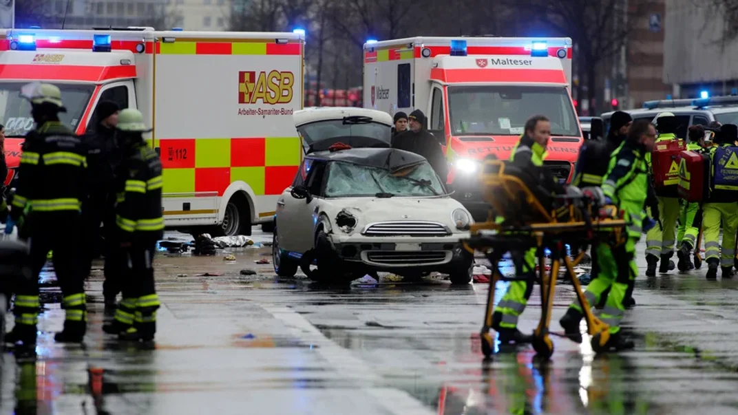 Поліція та екстрені служби стоять біля пошкодженого автомобіля, який, імовірно, в’їхав у демонстрантів у Мюнхені, 13 лютого 2025 року