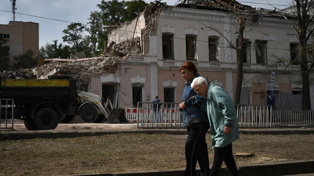 Люди проходят мимо сильно поврежденных зданий после последнего российского ракетного обстрела в Днепре, 12 сентября 2022 года
