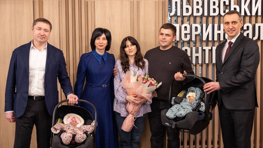 Двійнята з батьками та посадовцями, які приїхали на виписку