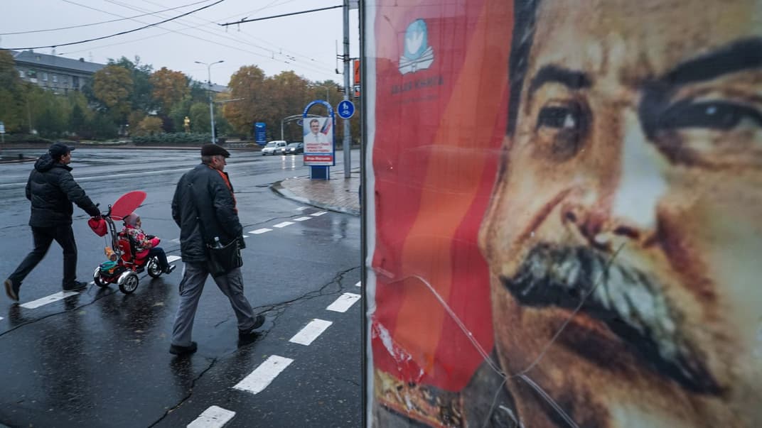 Люди проходят мимо портрета советского диктатора Иосифа Сталина, установленного в центре Донецка на востоке Украины