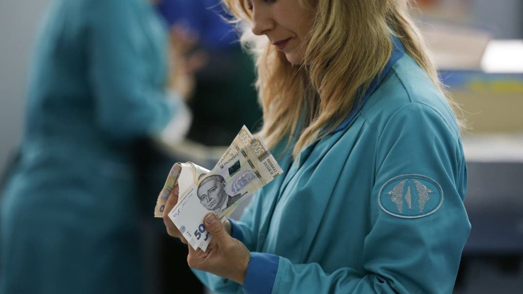 Працівниця банкнотно-монетного двору України тримає в руках щойно надруковані купюри номіналом 500 грн