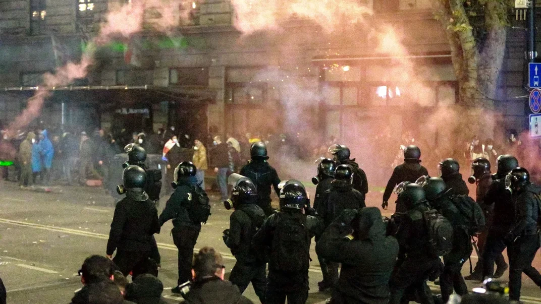Грузинская полиция проходит мимо протестующих во время беспорядков в Тбилиси, 30 ноября