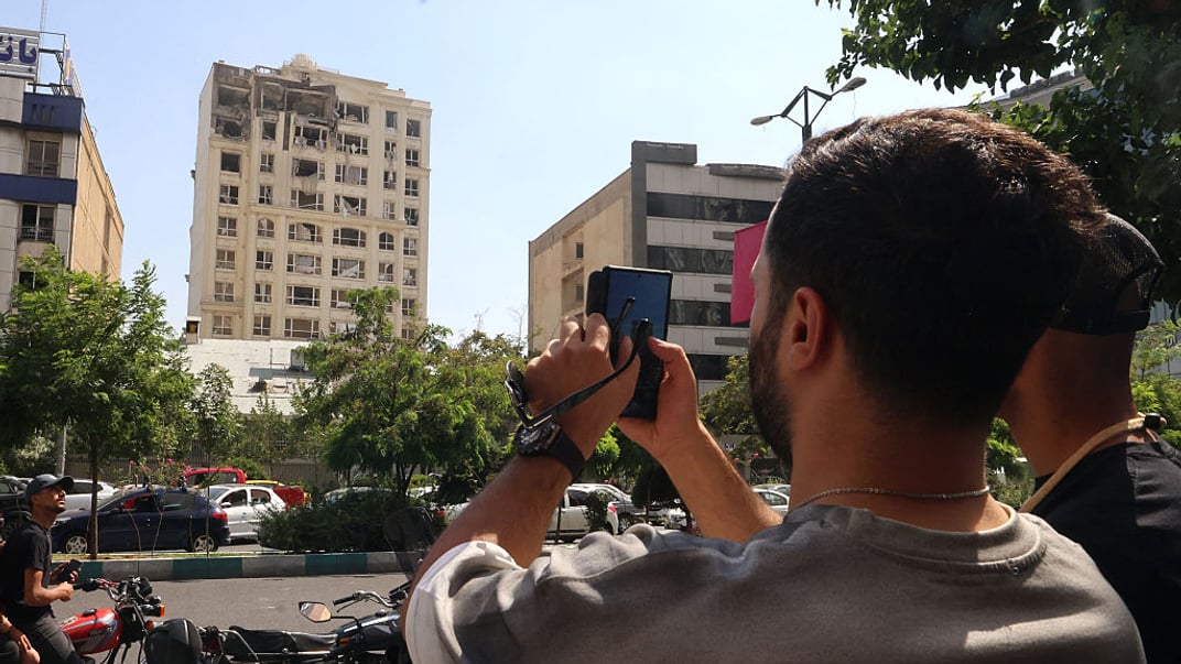 Чоловік фотографує будівлю в Тегерані, яка зазнала пошкоджень унаслідок ракетного удару Ізраїля по Ірану, 13 червня 2025 року