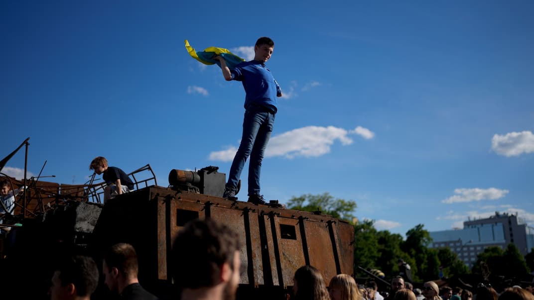 Хлопчик тримає український прапор на знищеному російському танку, розміщеному у центрі Києва як символ війни, 29 травня 2022 року