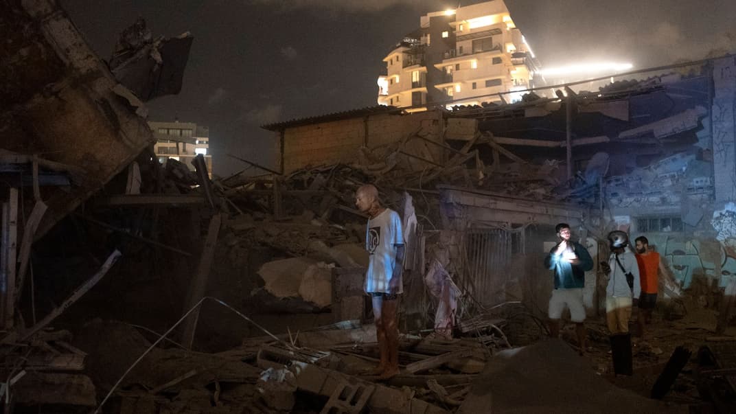 Люди смотрят на повреждения от ракеты, выпущенной из Сектора Газа по Тель-Авиву, 7 октября 2023 года