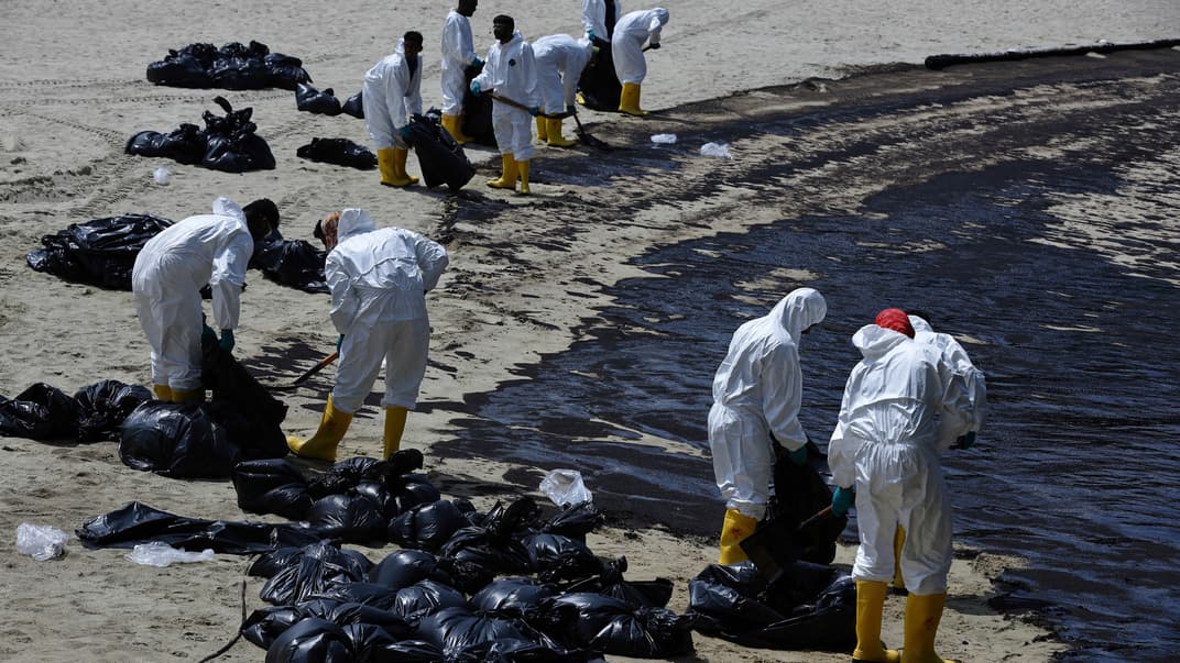 Рабочие убирают нефть вдоль пляжа Танджонг на Сентосе в Сингапуре, 16 июня 2024 года