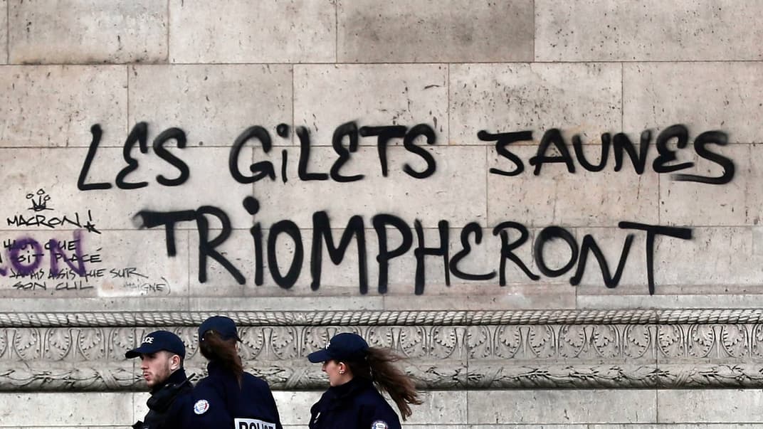 Співробітники поліції проходять повз написи «Жовті жилети будуть тріумфувати», нанесені на Тріумфальну арку, 2 грудня 2018 року
