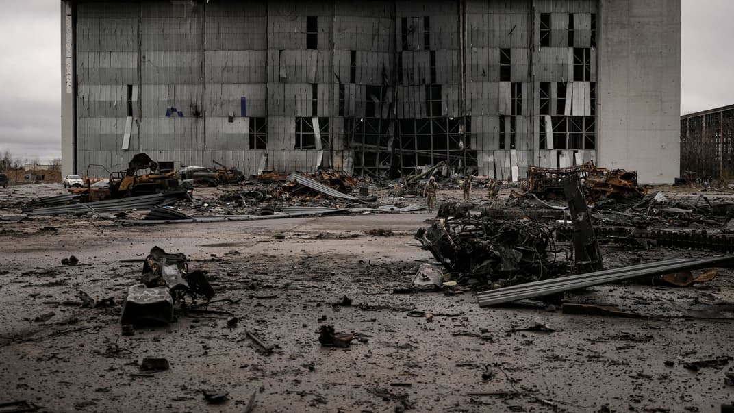 Украинские военные идут мимо уничтоженной российской техники в Гостомеле возле аэропорта «Антонов», 4 апреля 2022 года