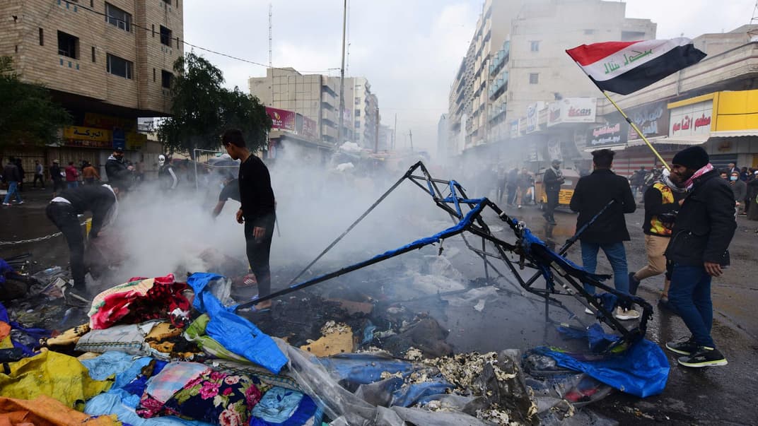 Иракские протестующие пытаются потушить огонь, который охватил их палатки на площади Тахрир в центре Багдада, Ирак, 25 января 2020 год