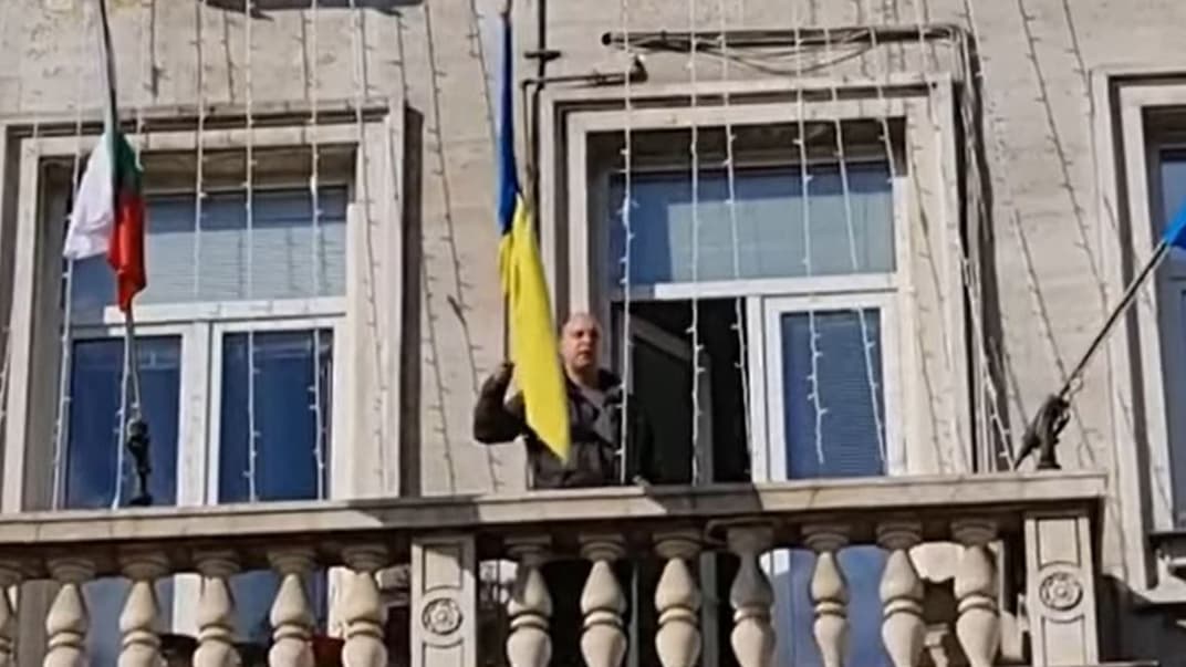 Кандидат у народні депутати Атанас Стефанов тримає в руках прапор України перед тим, як скинути його на землю з будівлі мерії Софії, 8 березня 2023 рік (скриншот)