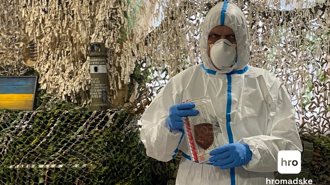 Експерт-криміналіст тримає в руках нашивку, знайдену на переданому тілі