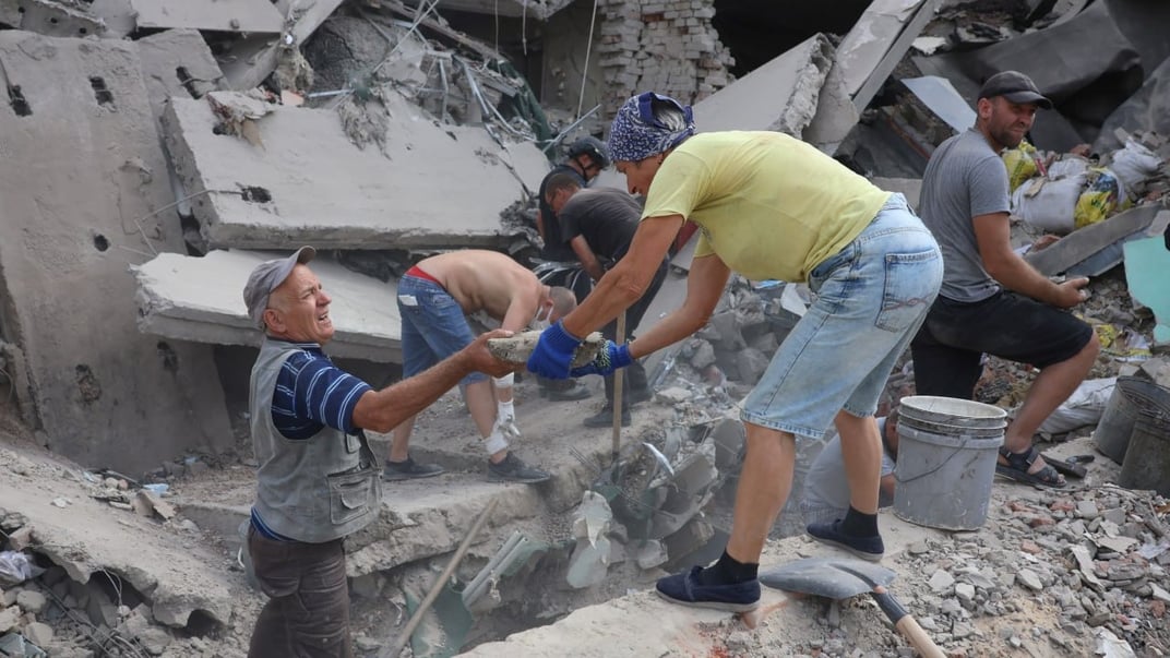 Жители Казачьей Лопани помогают спасателям и полицейским разбирать завалы на месте российского попадания в сельсовет 21 августа