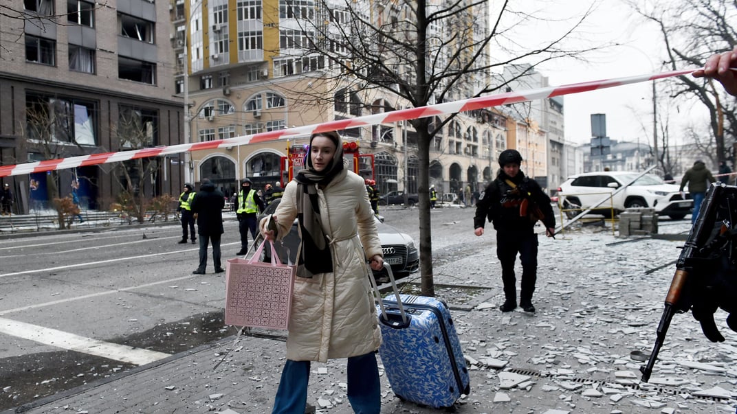 Ілюстративне фото. Жінка тягне валізу вулицею в Голосіївському районі після російського ракетного обстрілу в Києві, 20 грудня 2024 року