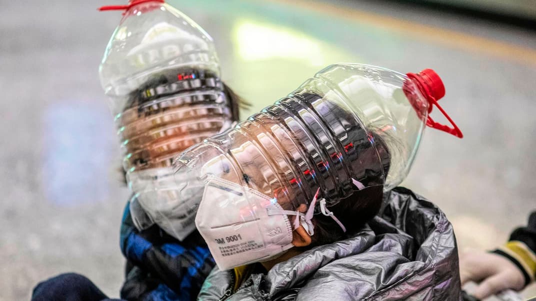 Діти в імпровізованому захисті для обличчя, виготовленому з пляшок з-під води, щоб захистити їх від можливого зараження коронавірусом, термінал прибуття аеропорту в місті Гуанчжоу, Китай, 1 лютого 2020 року