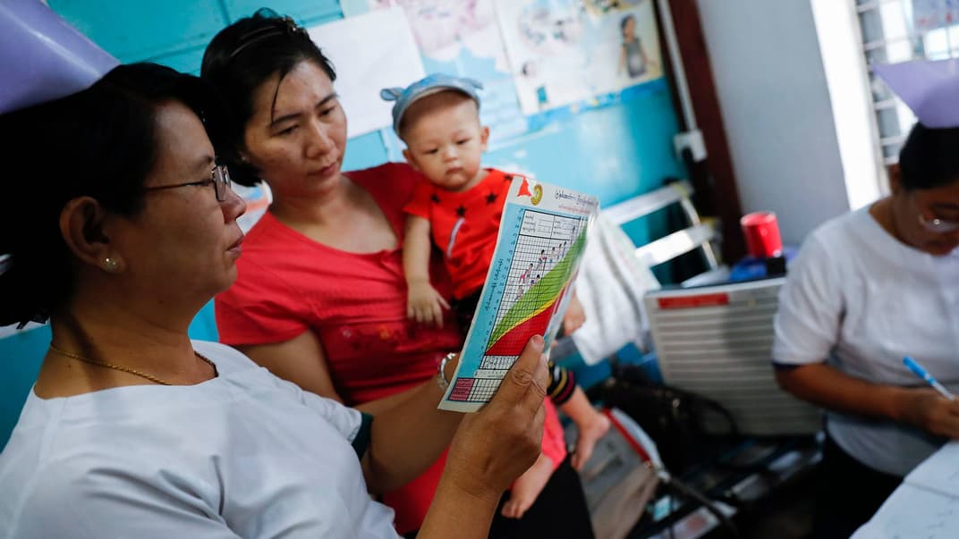 Медсестра з департаменту охорони здоров'я міської ради розповідає мамі малої дитини про програму імунізації проти кору та краснухи в Янгоні, М'янма, 14 лютого 2019 року