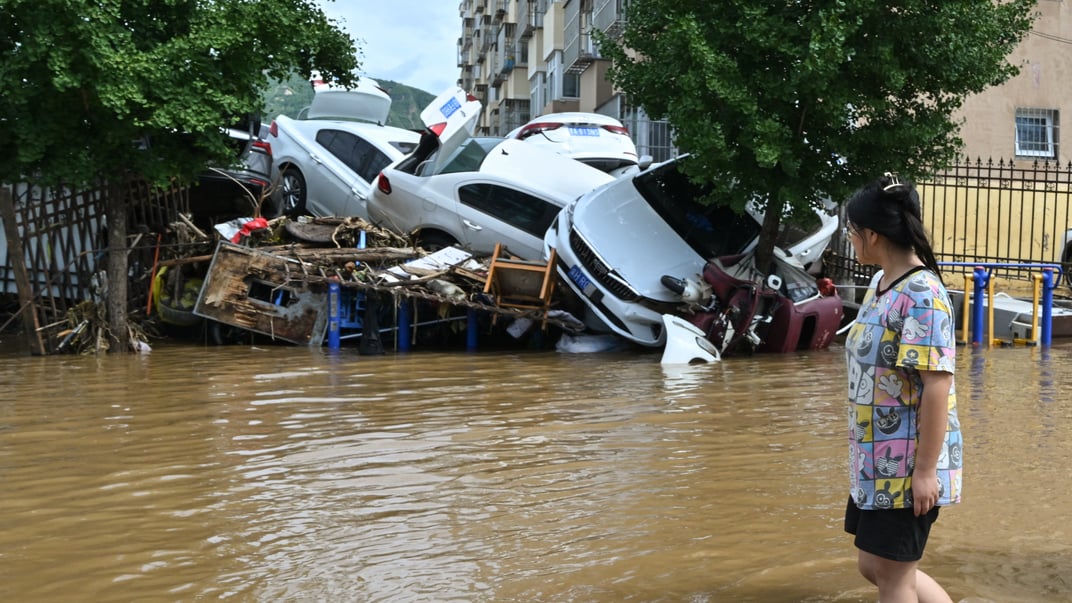Жінка проходить повз пошкоджені автомобілі в затопленому районі Міюнь на півночі Пекіна, 29 липня 2025 року