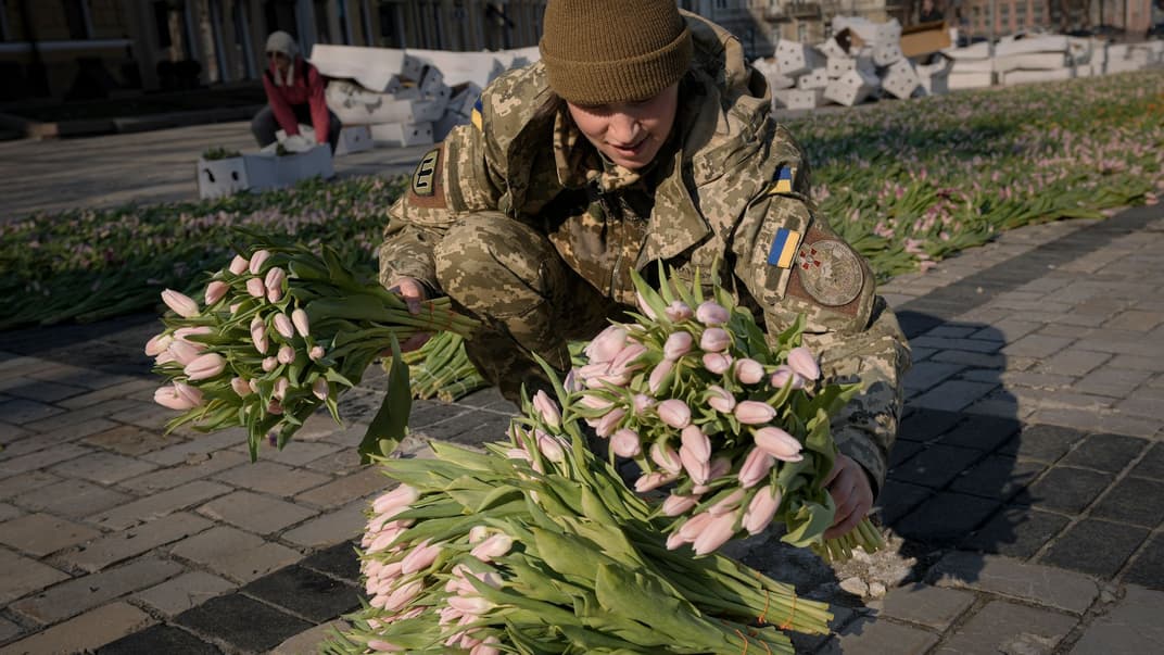 Українська військова разом з киянами викладає тюльпани у формі державного герба України на Софіївський площі у Києві, 18 березня 2022 року 