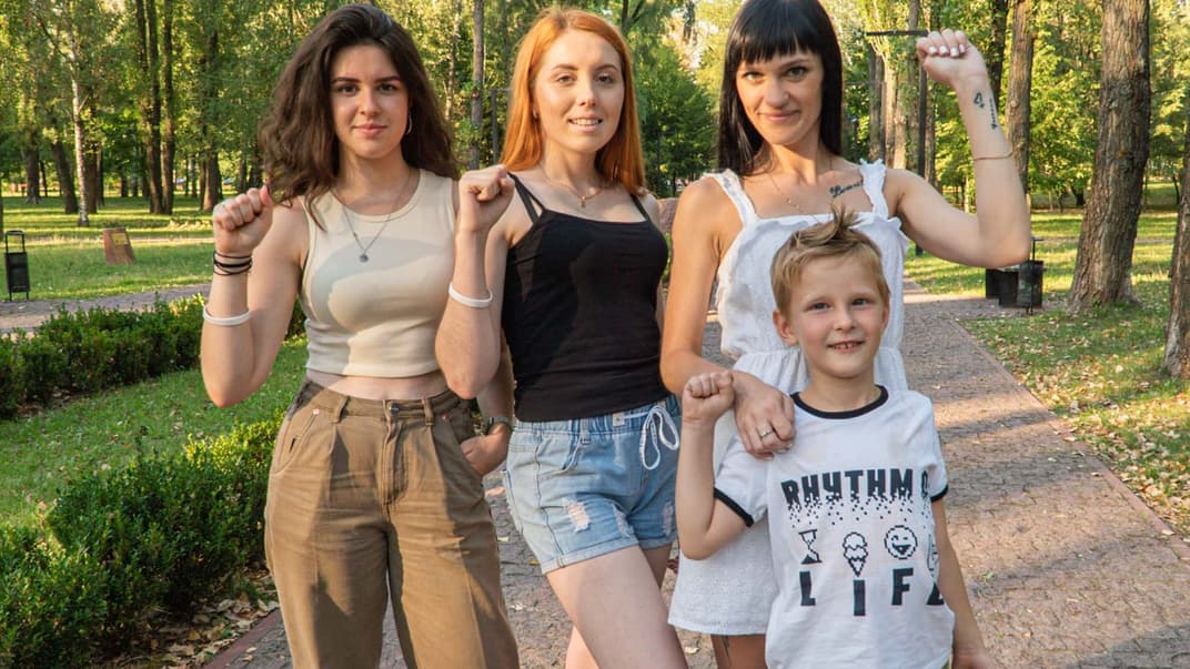 Политические беженки из Беларуси (слева направо) Ульяна Тикун, Божена Жолудь и Екатерина Куприянова с сыном в Киеве показывают победный жест белорусской оппозиции
