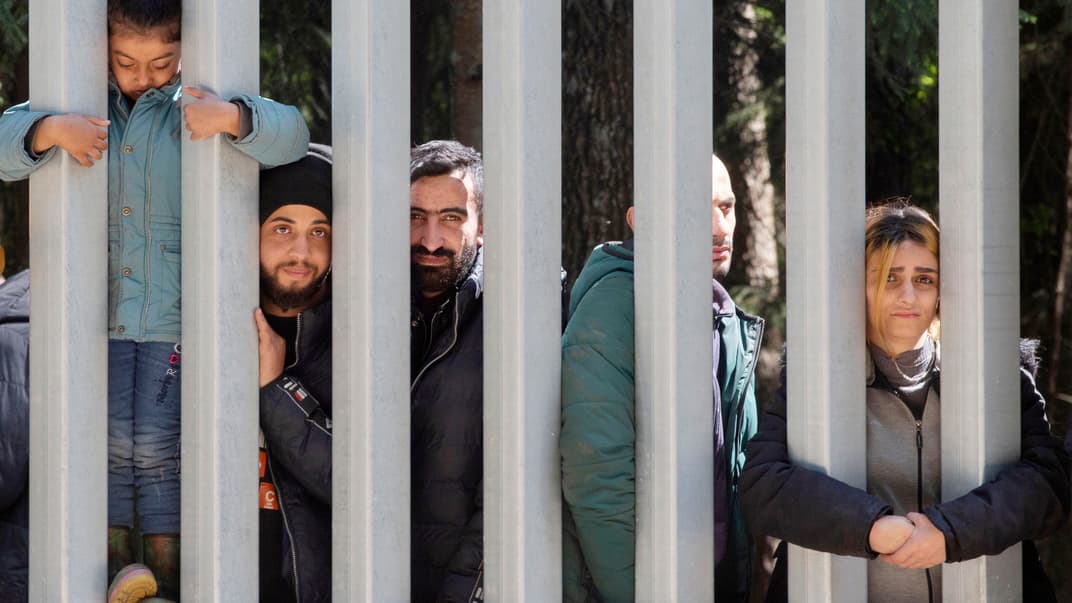 Ілюстративне фото. Нелегальні мігранти, які хочуть потрапити до Польщі з Білорусі, дивляться через металевий паркан, 28 травня 2023 року