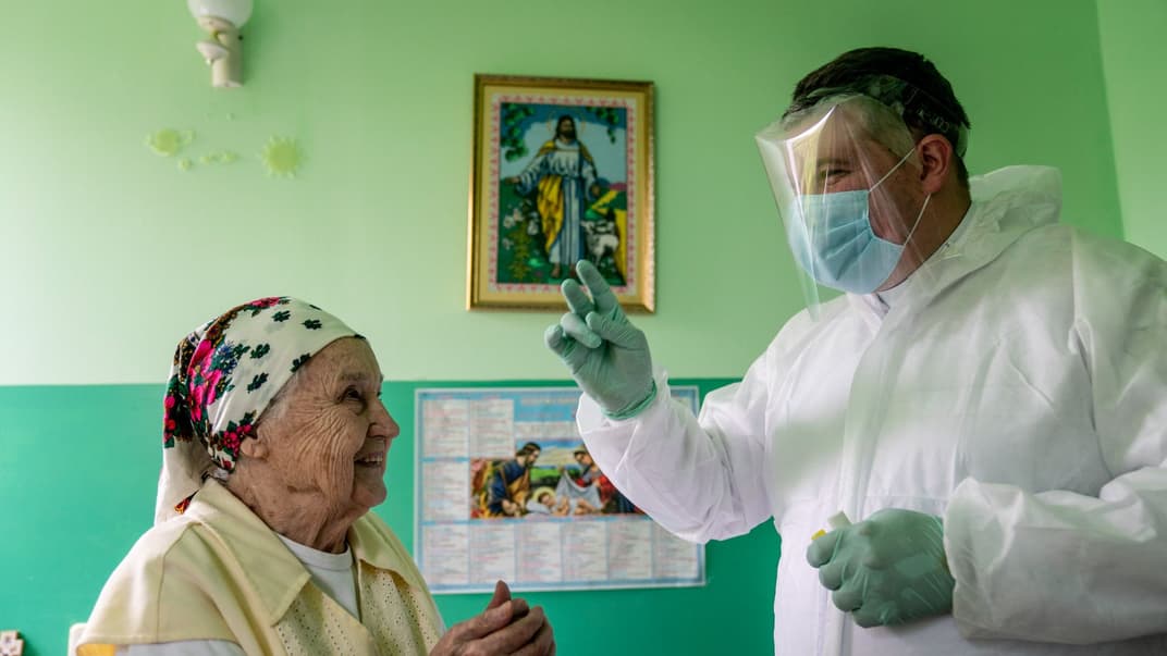 Отець Ярослав Рохман, священник Української греко-католицької церкви, одягнений у спеціальний костюм і щит для захисту від коронавірусу, благословляє пацієнтку хоспісу в Івано-Франківську, Україна, 28 травня 2020 року