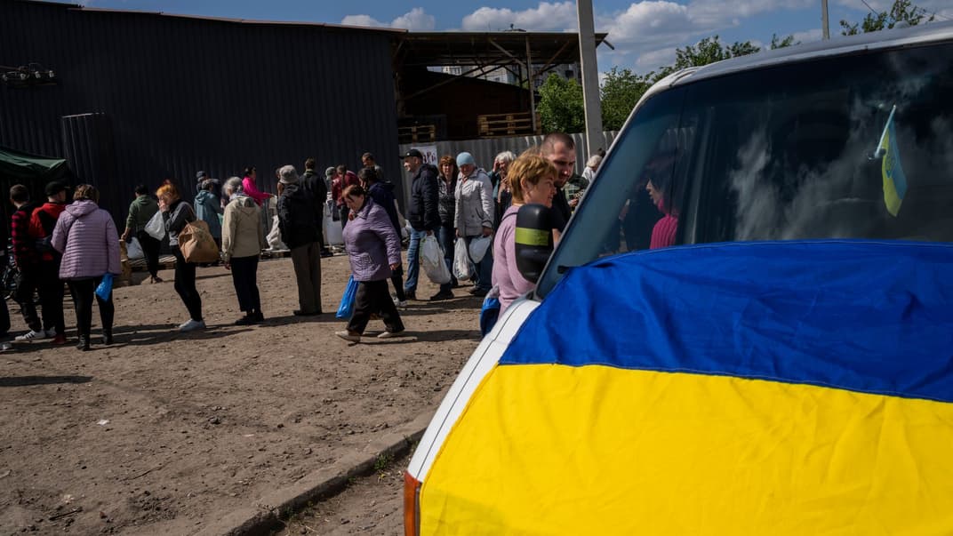 Люди стоять у черзі, щоб отримати борошно в пункті роздачі їжі у Харкові, 23 травня 2022