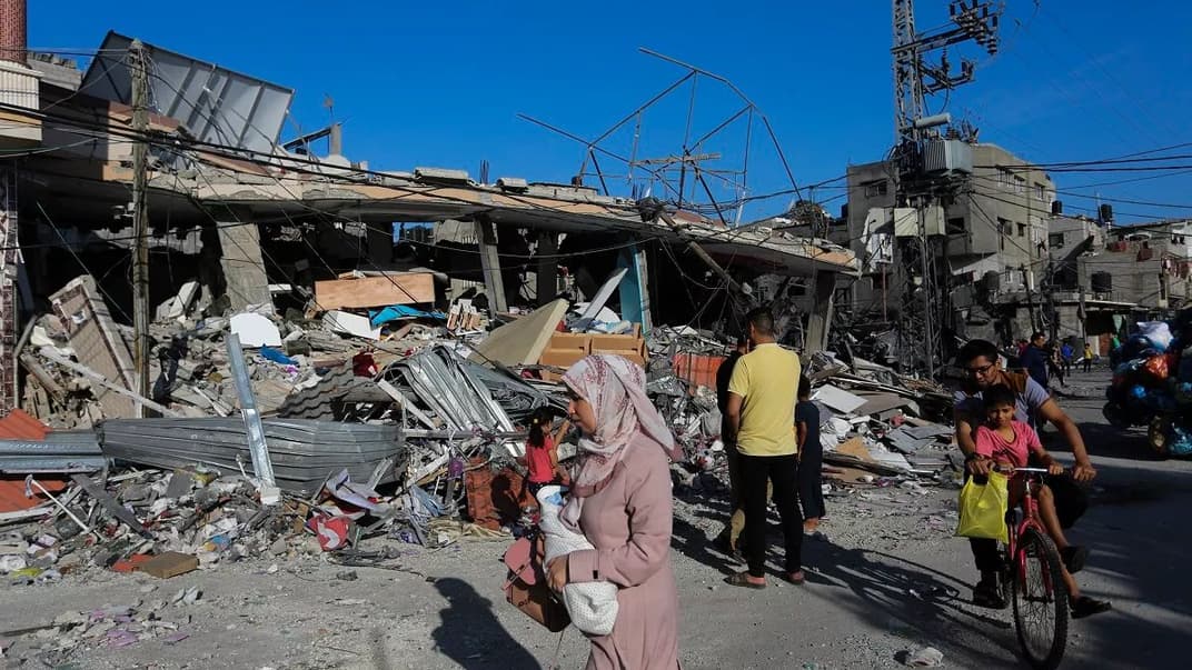 Палестинцы идут мимо разрушенного здания после израильского удара в Рафаху, Сектор Газа, 31 октября 2023 года