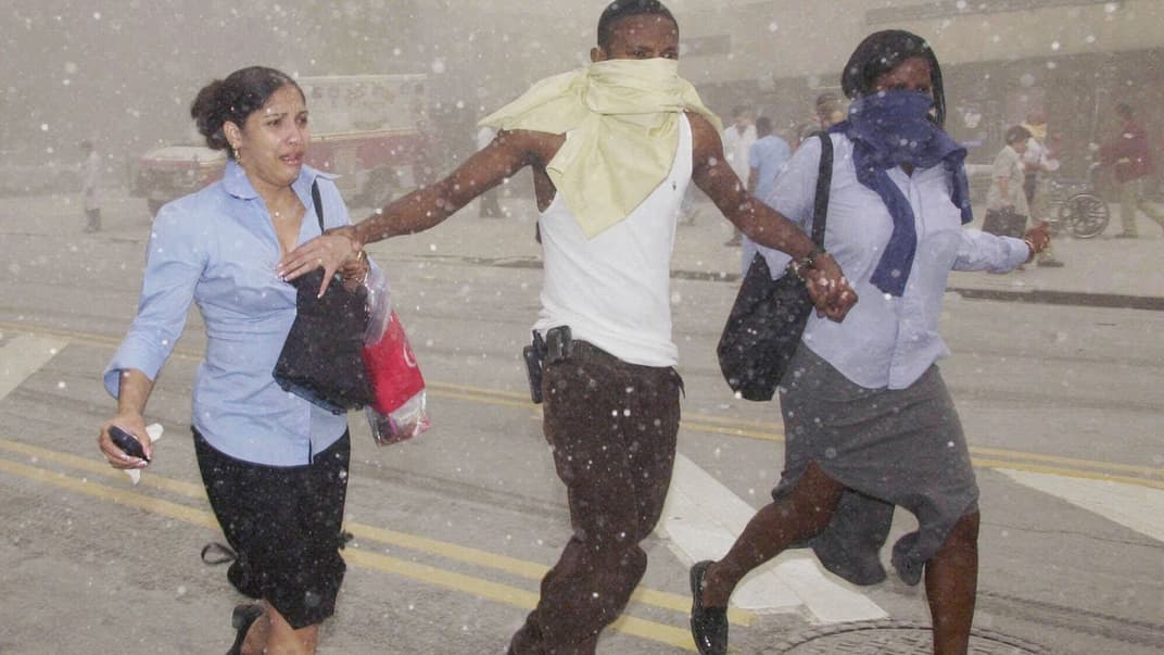 Три человека пробиваются сквозь облако едкой пыли после разрушения Всемирного торгового центра в Нью-Йорке в результате теракта 11 сентября 2001 года