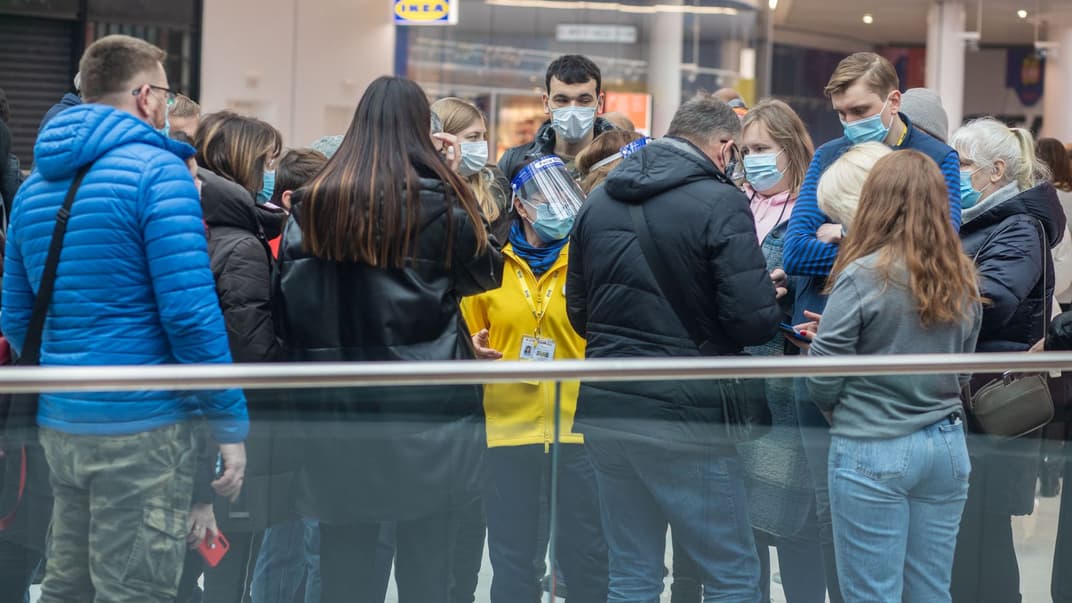 Працівниця магазину IKEA спілкується з людьми, які хочуть потрапити до магазину, але мусять чекати в електронній черзі через протиепідемічні обмеження.